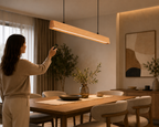 Person operating UNIKAA modern linear wood pendant light for dining room using remote control for lighting adjustment